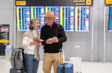 Senior asian couple with luggage checking passport planning trip showing travel preparation at...