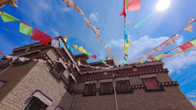 Colorful prayer flags flutter above a traditional stone-and-wood Tibetan-style house&mdash;capturing spiritual rhythm, architectural charm, and the interplay of culture and mountain wind in a peaceful ethni