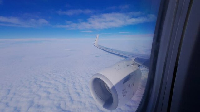 A view from an airplane window shows the aircraft wing and engine above soft cloud layers&mdash;capturing sky gradients, smooth motion, and the tranquil aesthetic of high-altitude travel.