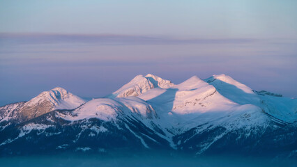 Snowy Mountain Peaks Bathed in Golden Light A Majestic Alpine Vista under Pale Blue Skies and Wispy Clouds at Sunset