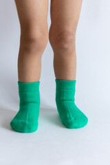 Legs of a 2 year old baby in warm green socks on a white background