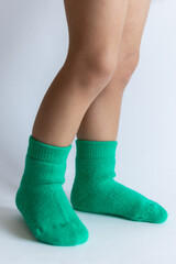 Legs of a 2 year old baby in warm green socks on a white background