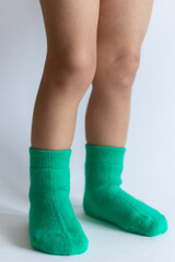 Legs of a 2 year old baby in warm green socks on a white background