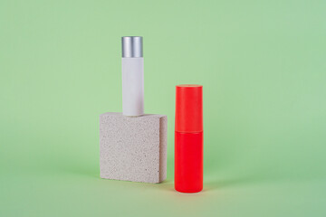 White tube and red spray on light white podiums. White blank unbranded flacons with cosmetology products. Professional concept of skin care on green background.