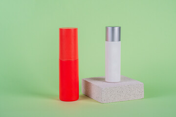 White tube and red spray on light white podiums. White blank unbranded flacons with cosmetology products. Professional concept of skin care on green background.