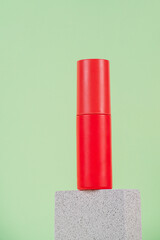 Cosmetic red bottle. Womens cosmetic accessory for makeup with stylish props on green background.