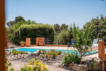 Jardin méditerranéen avec piscine et touches de terre cuite sous un ciel d’été bleu
