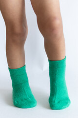 Legs of a 2 year old baby in warm green socks on a white background