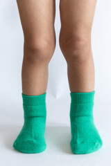 Legs of a 2 year old baby in warm green socks on a white background