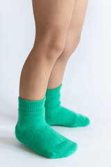 Legs of a 2 year old baby in warm green socks on a white background