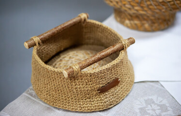 Handcrafted wicker basket with wooden handles displayed on a textile surface