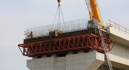 Fototapeta premium Bridge under construction with rebar and crane lifting equipment. Modern engineering work on an elevated highway project concept.