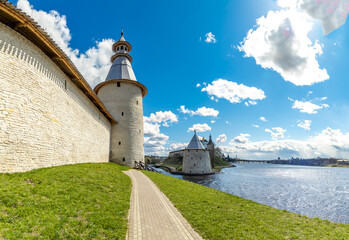 Vysokaya Tower of Pskov Kremlin along Velikaya River's green bank, with main fortress towers...