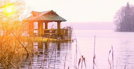 Serene lakeside gazebo at sunset surrounded by nature and reflections on the water