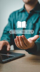 Man using laptop with virtual icon of user guide book and search bar for digital instructions and online documentation.