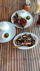 A rustic rural setup with grilled chicken inasal, pork liempo, rice, and iced coffee served in a bamboo table showing an authentic traditional local Filipino food in the Philippines