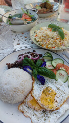 Sumptuous Filipino breakfast spread featuring rice, fried eggs, bistek or karne frita with bowls of chicken adobo and tinola soup. Authentic local food from the Philippines