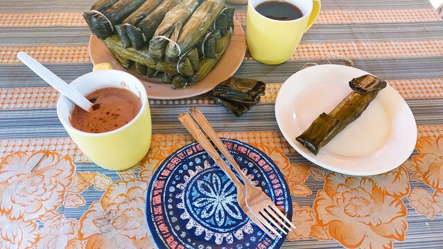 Glutinous rice cakes wrapped in banana leaves called suman or budbud paired with coffee, traditional and authentic local Filipino snack from the Philippines