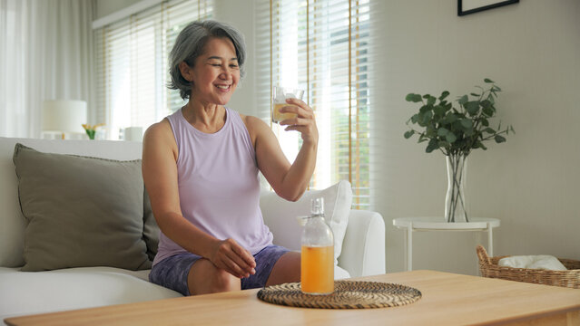 Asia adult people middle age happy old woman pour weight loss tea fiber juice drink kombucha gut health care diet detox sit at home sofa elder aging asian aged female. Fresh bottle medical food relief