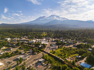 A freight train crossing Mount Shasta town, with snow covered Mount Shasta volcano in the...