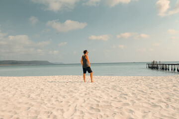 A man gazes at the ocean near an old pier in a tranquil setting in Koh Rong Sanloem, Sihanoukville, Cambodia