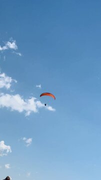 Man paragliding over coastal cliffs on a sunny day.