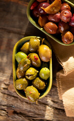 Olives, homemade marinated colorful olives with herbs and spices on rustic table, close up. Healthy Mediterranean vegan food. Top view, flat lay, vertical image 