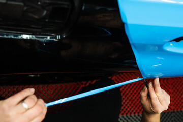 Precision PPF wrapping and detailing on car panel using sharp blade to trim wrap with accuracy. Car...