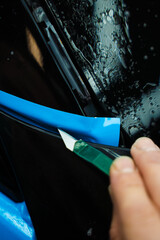 Cutting blue PPF with blade. Cutting blue paint protection film with blade during detailing job...