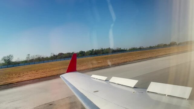 Fixed shot of the wing of plane with the speed reducers on, stoping on the airstrip
