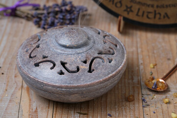 Close-up of an incense bowl in which incense is smoked on a glowing coal. The fragrant smoke rises gently through the perforated lid.