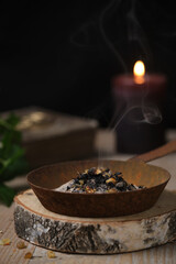 Incense ritual at wheel of the year festival Samhain with frankincense, myrrh and dried herbs in dark and moody atmosphere