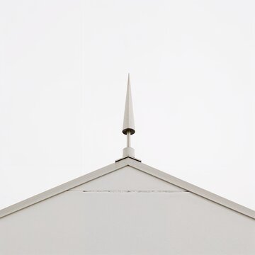 White rooftop lightning rod with sharp conical tip mounted on minimal facade under clear sky