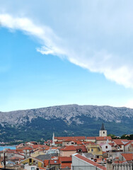 An elevated view over the red-tiled roofs of Baska on Krk Island reveals the prominent bell tower...