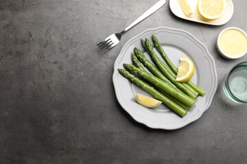Tasty cooked asparagus served with lemon on grey table, flat lay. Space for text