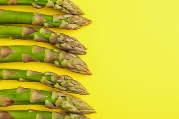 Fresh ripe raw asparagus on yellow background, flat lay. Space for text