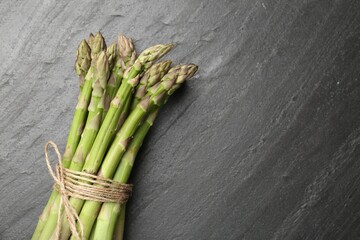 Fresh raw asparagus spears on black table, top view. Space for text