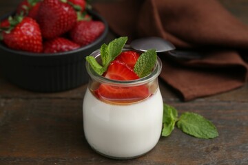 Tasty panna cotta with caramel, strawberries and mint on wooden table, closeup