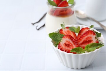 Tasty panna cotta with strawberries, mint and vanilla pods on white table, closeup. Space for text