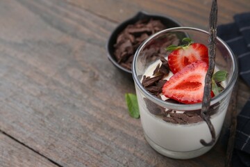Tasty panna cotta with chocolate, strawberry, mint and vanilla pods on wooden table, closeup. Space for text