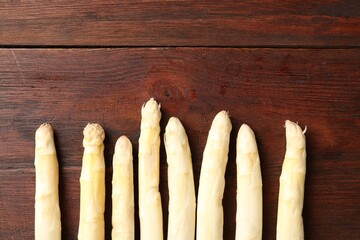Many raw asparagus spears on wooden table, flat lay. Space for text