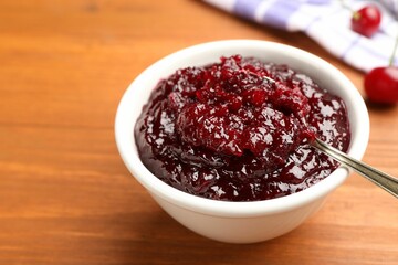 Tasty cherry jam and fresh fruits on wooden table, closeup