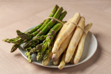 Different raw asparagus spears on wooden table, closeup