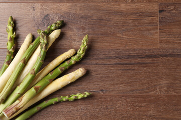 Different raw asparagus spears on wooden table, flat lay. Space for text
