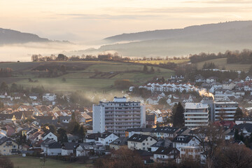 Herbstliche Sonnenaufgangsstimmung im Nebel mit Blick auf die Kleinstadt Neu-Anspach, aufgenommen von Rod am Berg im Taunus im hessischen Hochtaunuskreis in Deutschland 
