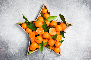 Star-shaped box with fresh tangerines. Green tangerine leaves. Free space for text.