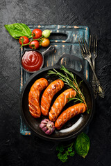 Cast iron pan with fried pork sausages. Top view. Barbecue or grill background.