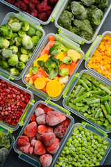 Various vegetables and berries frozen in plastic containers. Top view. Frozen food. Vertical photo.