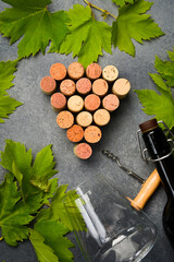 Arrangement of wine corks in the shape of a bunch of grapes and grape leaves on a stone table. Top...