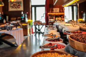 Rich hotel breakfast buffet with bowls of fresh fruits, cereals, nuts, cheeses, and cold cuts....